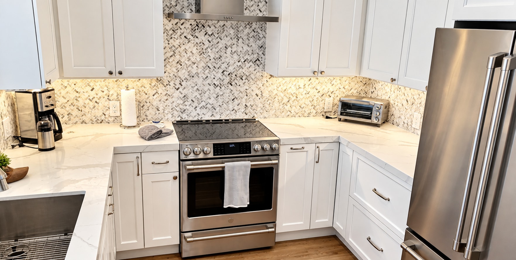 White shaker kitchen with herringbone backsplash and quartz countertops