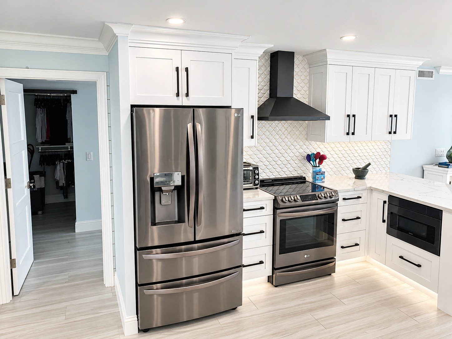 White shaker kitchen with black stainless appliances and scallop backsplash