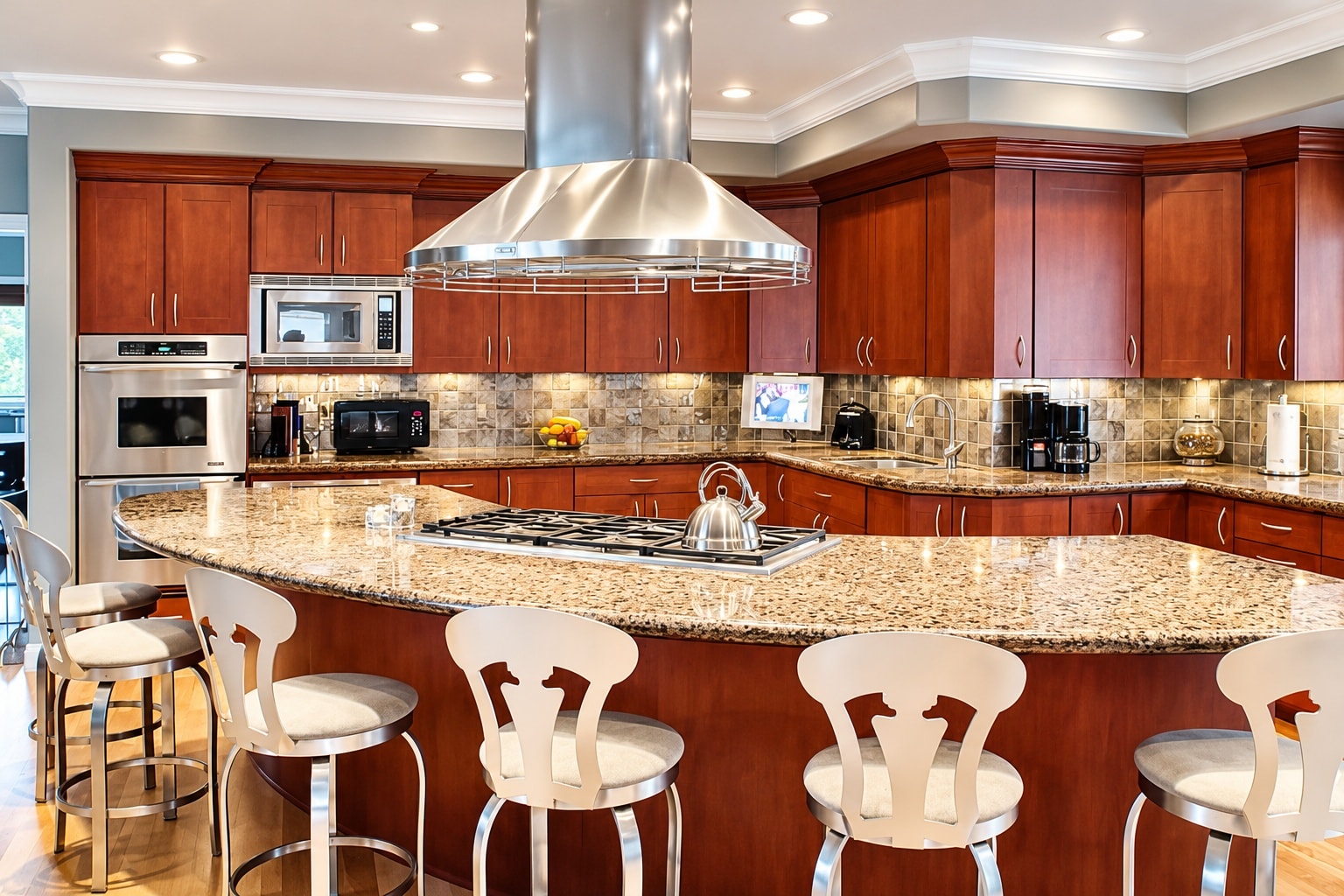 Kitchen with large curved granite island and stainless range hood