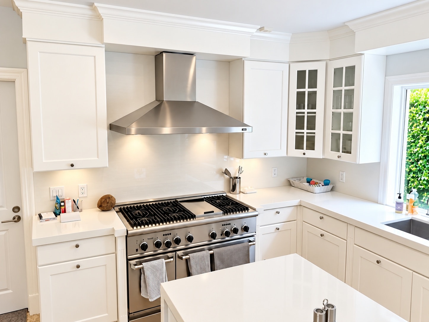 White kitchen with professional range and stainless hood