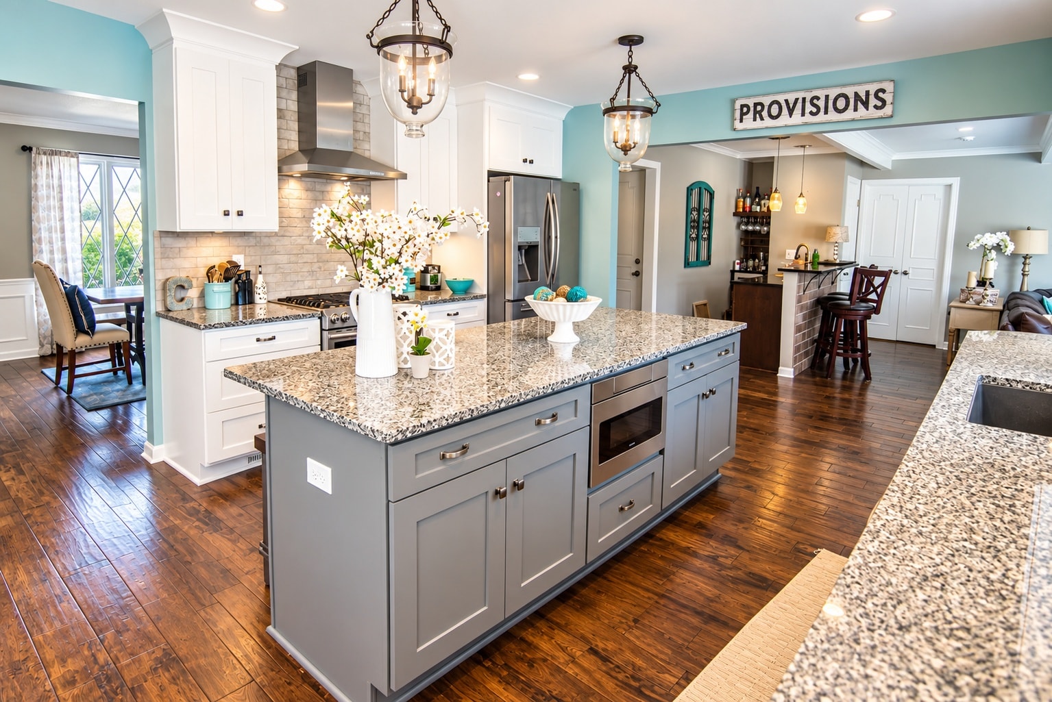 Open-concept kitchen with gray island and pendant lanterns