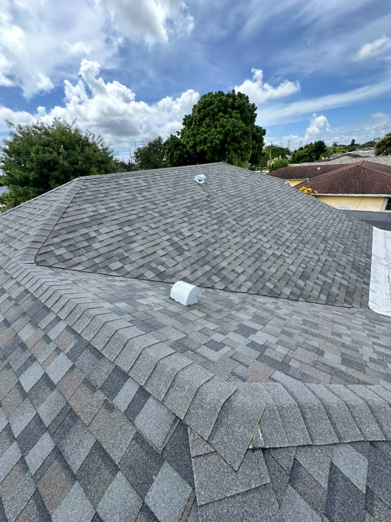 Close-up of gray asphalt shingle roof with vent pipe