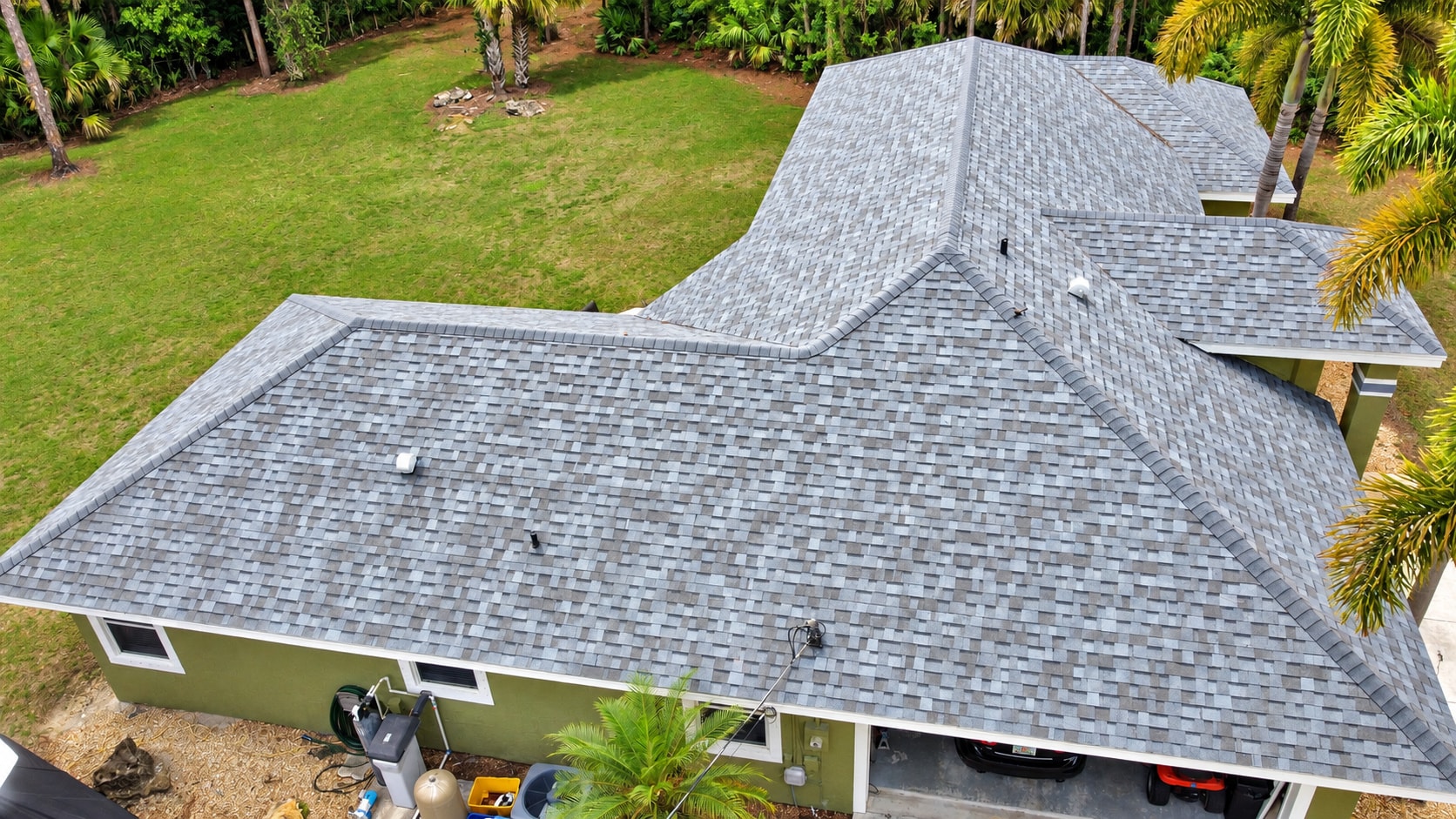 Aerial view of gray shingle roof on Florida home with palm trees