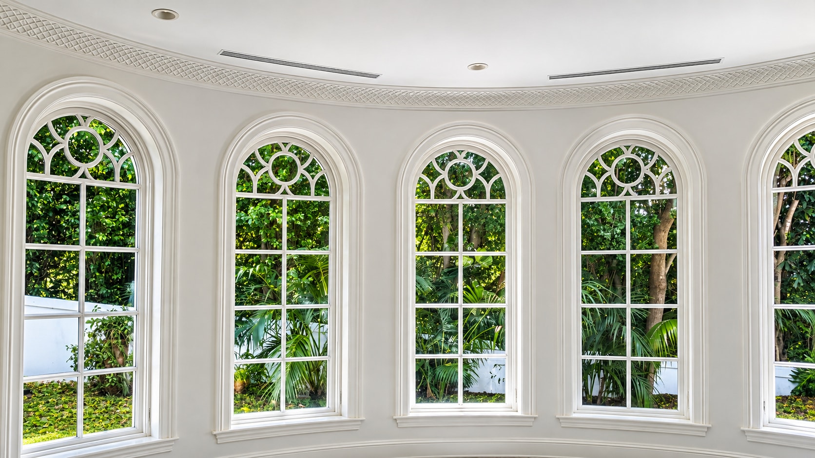 Elegant arched windows with white frames overlooking lush foliage